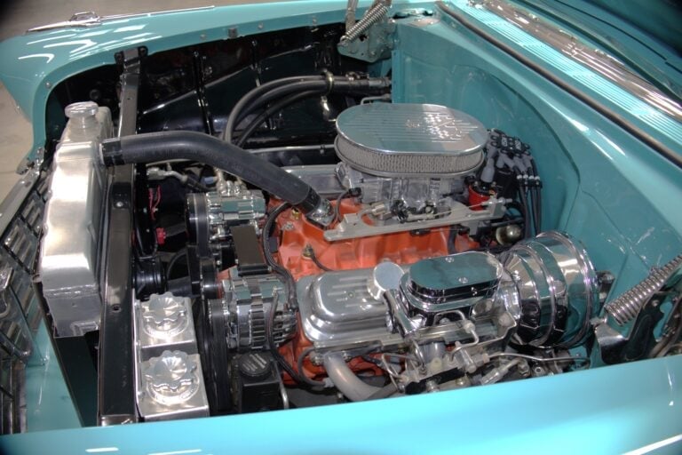 Turquoise classic car engine bay showing polished chrome details and orange-painted V8 engine block with air filter