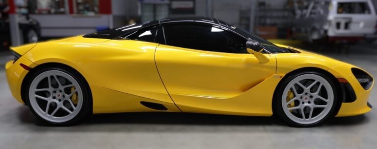 Bright yellow sports car with open door displayed in garage setting