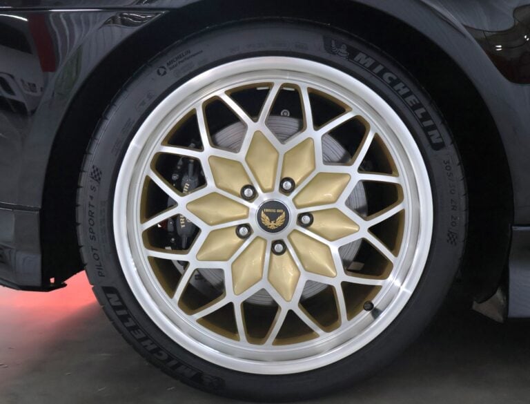 Close-up of a car wheel with gold and silver multi-spoke alloy rim design mounted on black tire