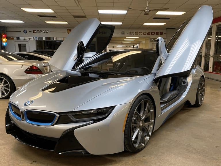 White BMW i8 sports car with open gullwing doors displayed in a showroom