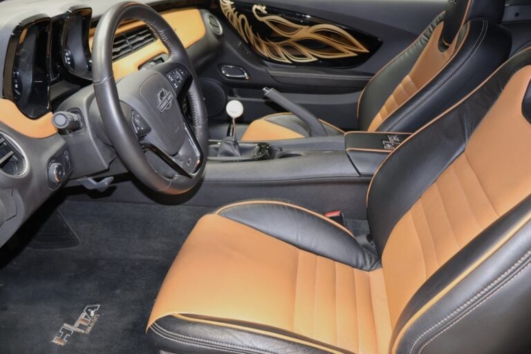 Interior of a sports car with tan and black leather seats, black steering wheel, and dashboard view