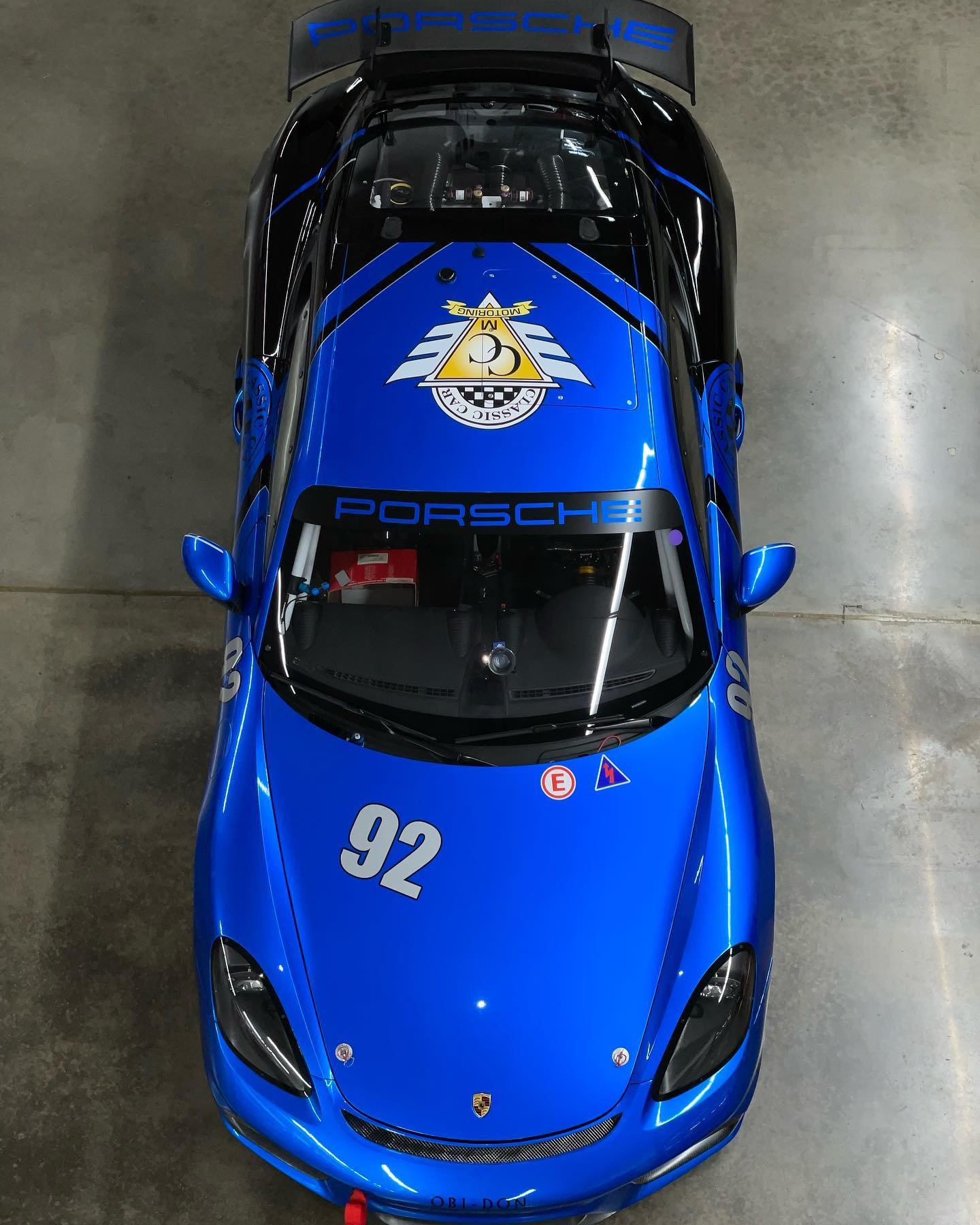 Top-down view of a blue Porsche race car with number 92 and yellow emblem on hood